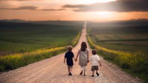 3 children walking down road at sunrise